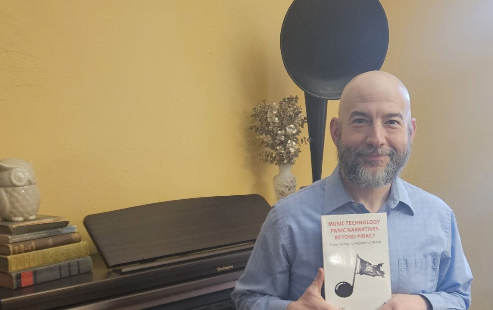 David Arditi holding his new book Music Technology Panic Narratives Beyond Piracy: From Taping to Napster to TikTok