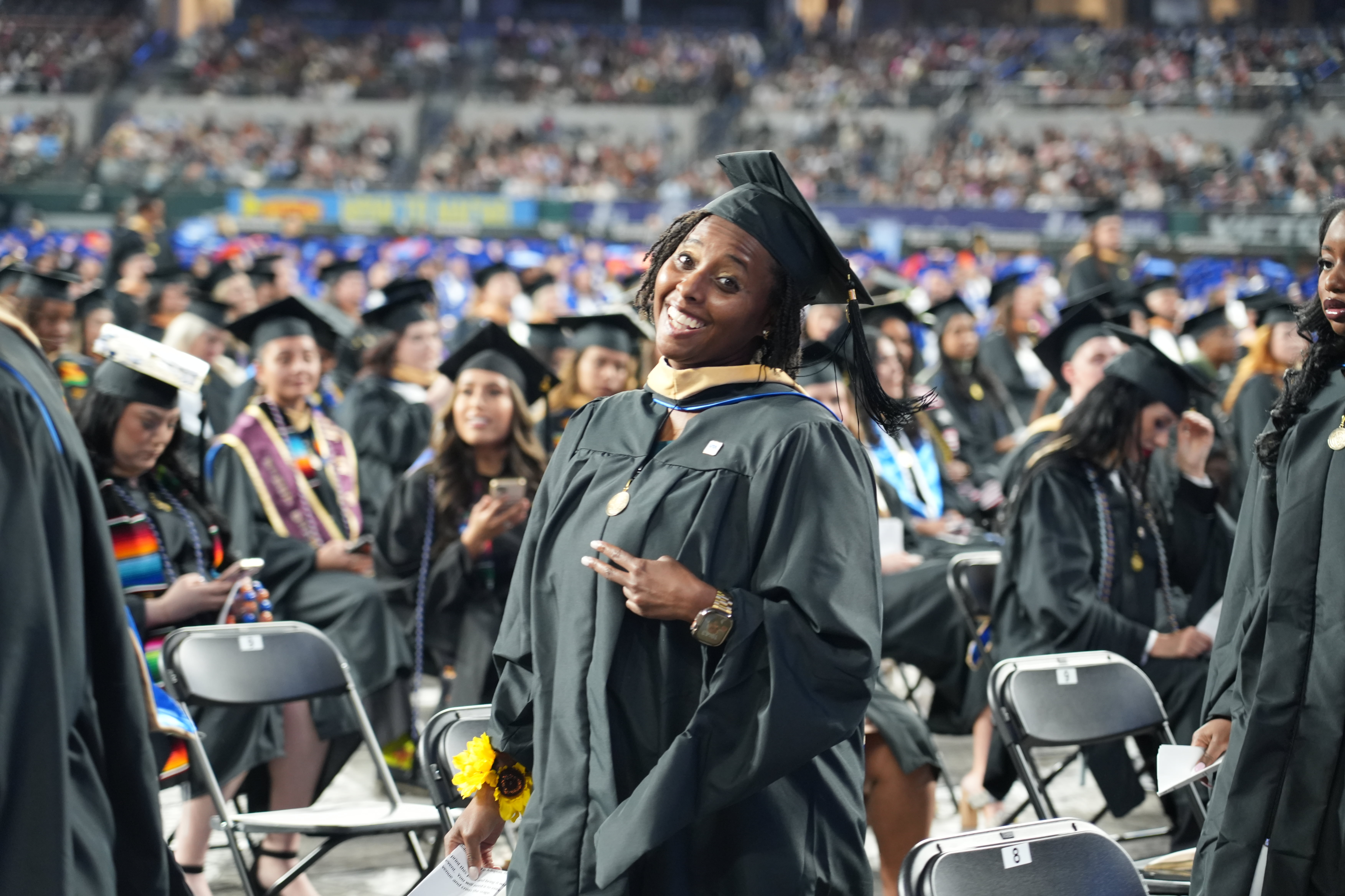 A UTA School of Social Work Master's student gives a peace sign during the Fall 2025 UTA Commencement Ceremony. (Photo by Doughlas Gutierrez)