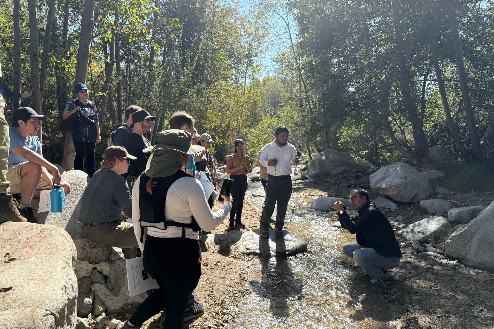 Image shows Dr. Adnan Rajib, lower right, in a creek explaining water research to students " style=" height:1080px; width:1620px" _languageinserted="true" src="https://cdn.prod.web.uta.edu/-/media/80fcfbd2d29146ac87adc4601a95ba8f.jpg