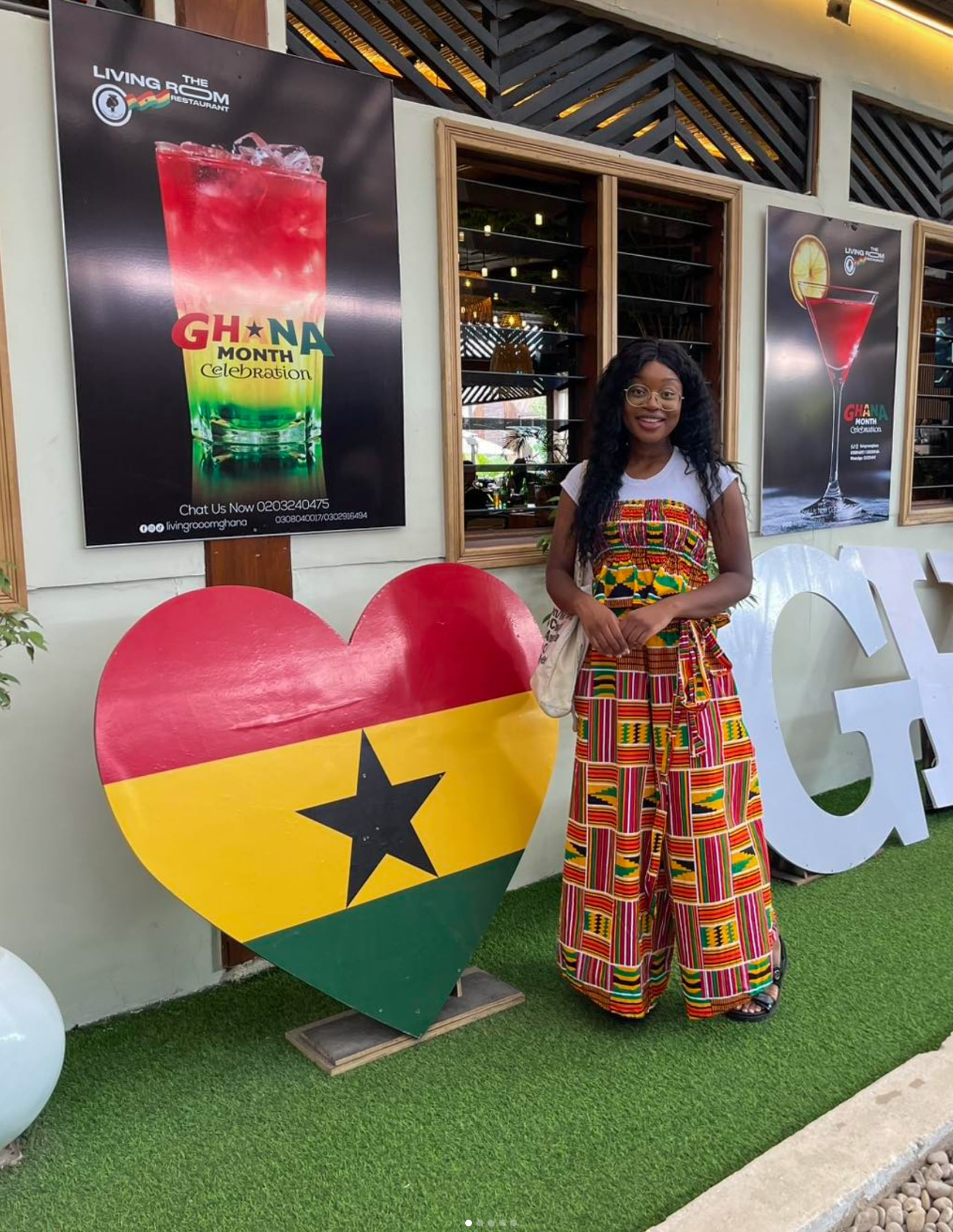 Danielle Quaye standing next to a sign that says I heart Ghana.
