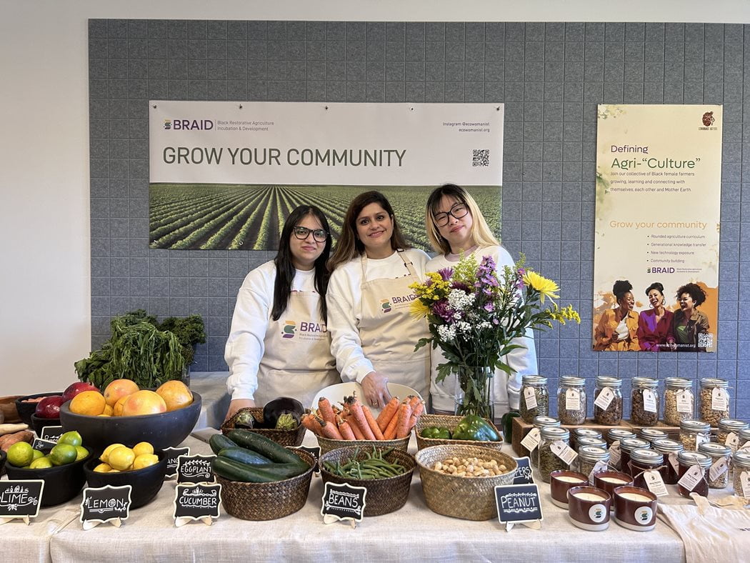 Ananya Singh with her colleagues standing behind produce and jars