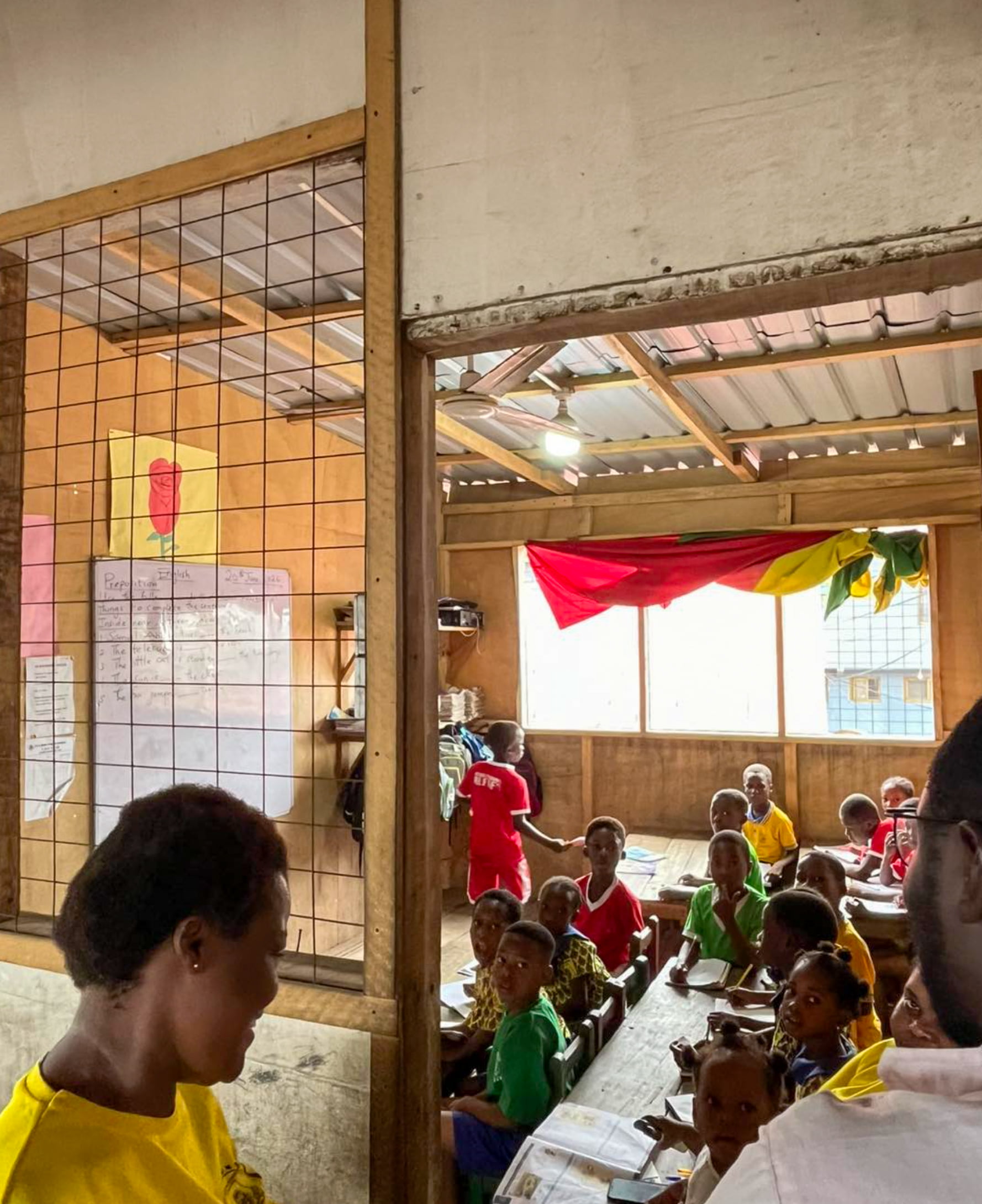 Children at desks with paper and pencils.