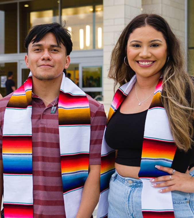 two hispanic students smiling on uta campus