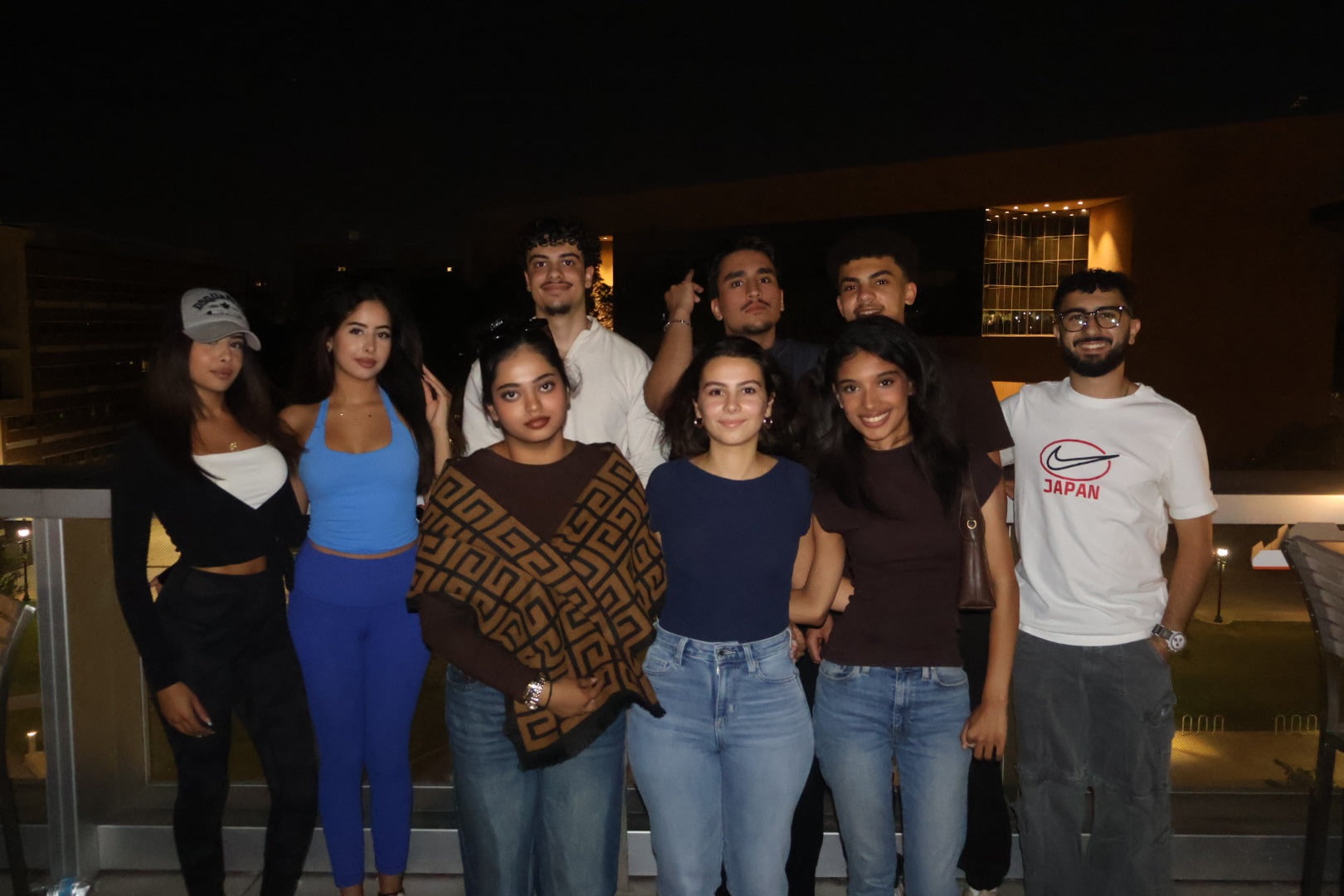 group of men and women smiling in front of a building at night