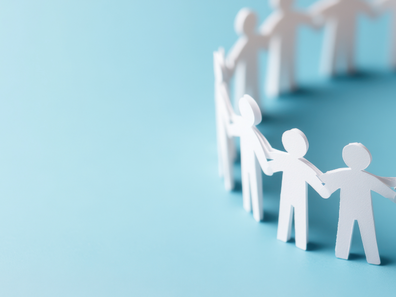 White paper figures connected in a line, with two figures holding hands in the foreground against a soft light-blue background.