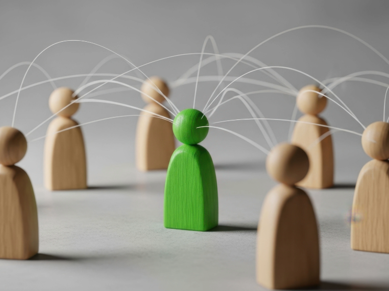 Wooden figures connected by overlapping white lines, with a bright green figure highlighted at the center of the network.