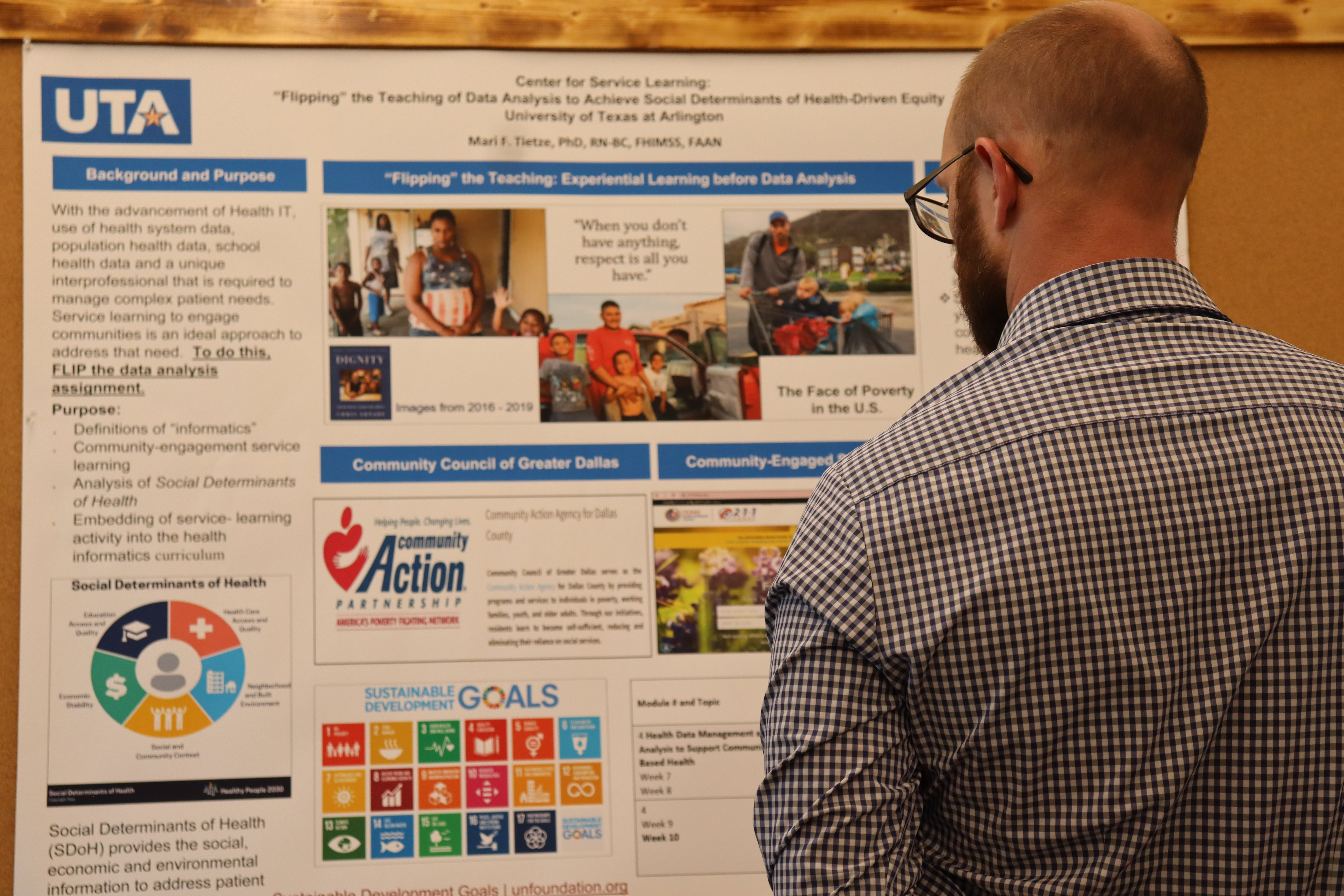 male person with glasses looking at a poster board