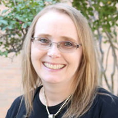 picture of Angela Liegey-Dougal, dressed in a dark shirt with a necklace and glasses on