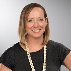 picture of Jaya Davis, dressed in a dark short-sleeve with a long pearl necklace