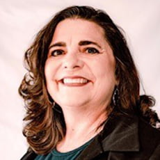 picture of Lashaunn Bold, dressed in a blazer over a formal shirt with dangling earrings in front of a neutral background