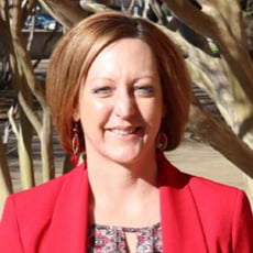 picture of Shanna Banda, dressed in a blazer over a patterned shirt and dangling earrings