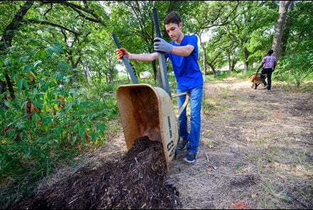 student using a wheelbarrow to put dirt on the ground