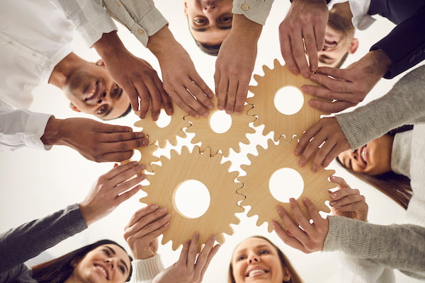 people in a circle holding gold wheels and cogs