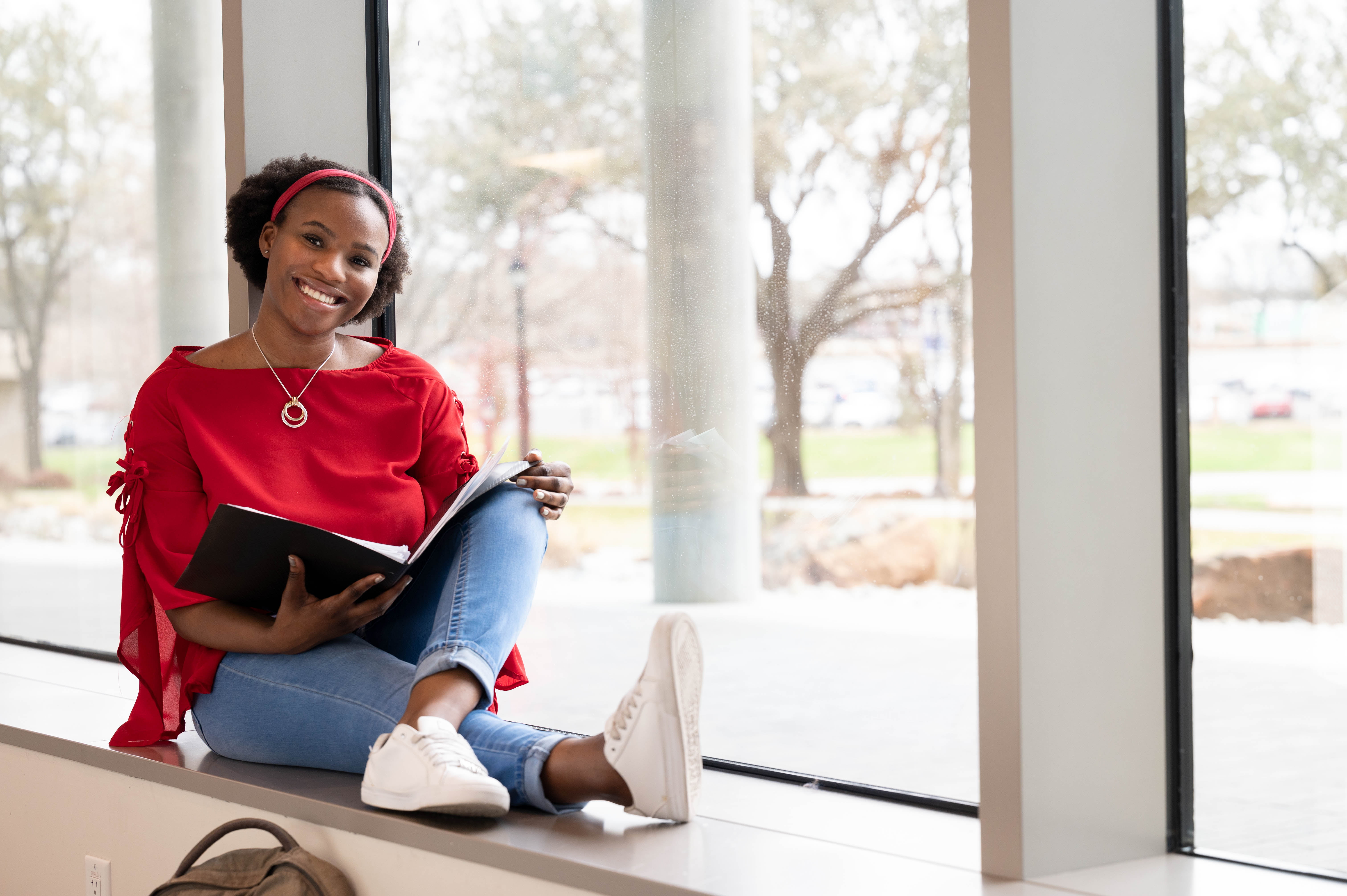 Smiling student sitting with an open binder in their lap