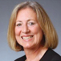 Becky Garner smiling in front of a neutral background and dark blouse