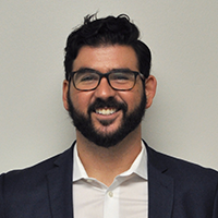 headshot of Dr. James Austin Sandy in front of a neutral background, wearing a suit and glasses