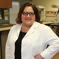 headshot of Jennifer Lynn Roye wearing glasses and a necklace, along with a light blazer of a dark shirt