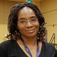 headshot of Dr. Sonja Ezell wearing a dark shirt, glasses, and a lanyard