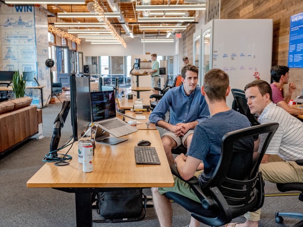 three students talking in front of a desktop