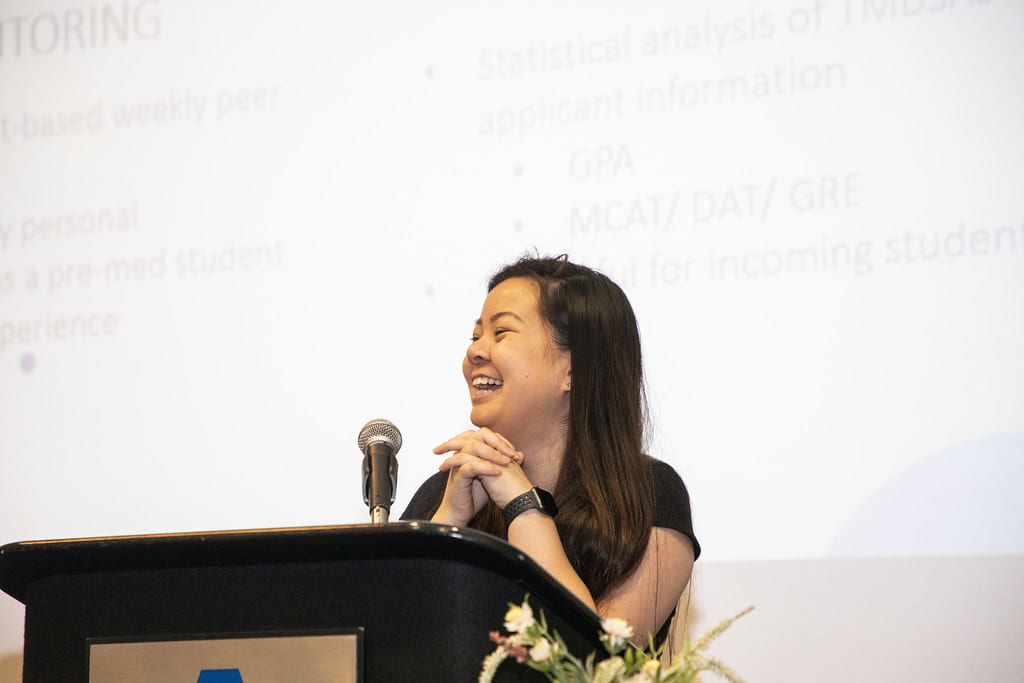 lady giving a presentation at a U T A event, her presentation displayed behind her