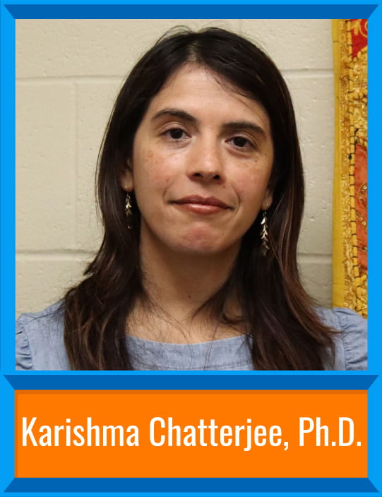 Karishma Chatterjee stands in front of a brick wall with a light blouse and earrings. There's a border around the image and her name is at the bottom, "Karishma Chatterjee, Ph.D."