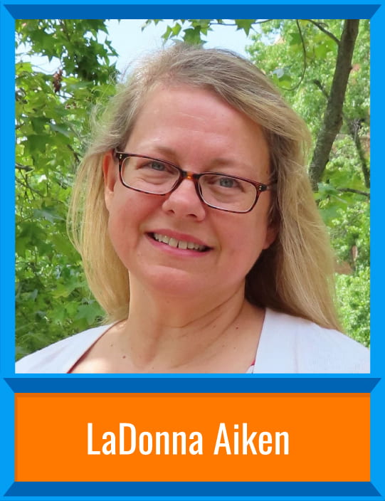 LaDonna Aiken stands in front of trees with a light cardigan and dark-rimmed glasses. There's a border around the image and her name is at the bottom, "LaDonna Aiken."