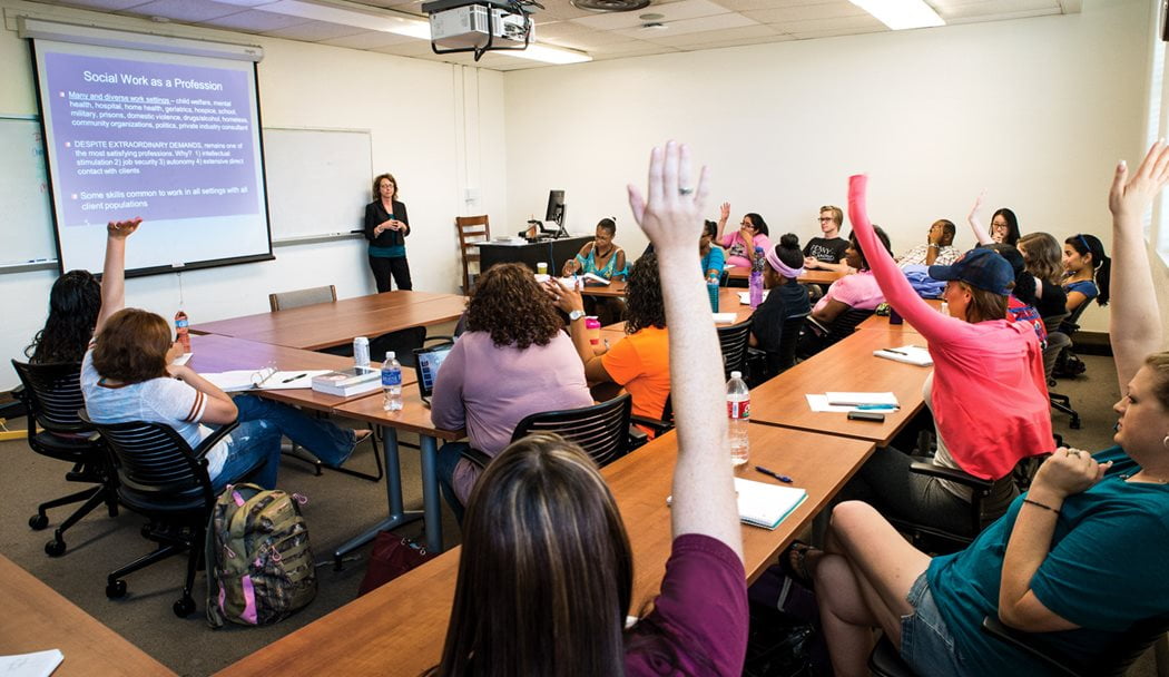 Students raising hands in a social work class