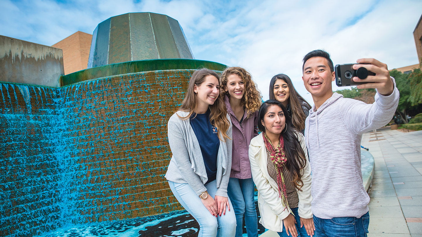 Students taking selfie in front of blue fountain during Homecoming