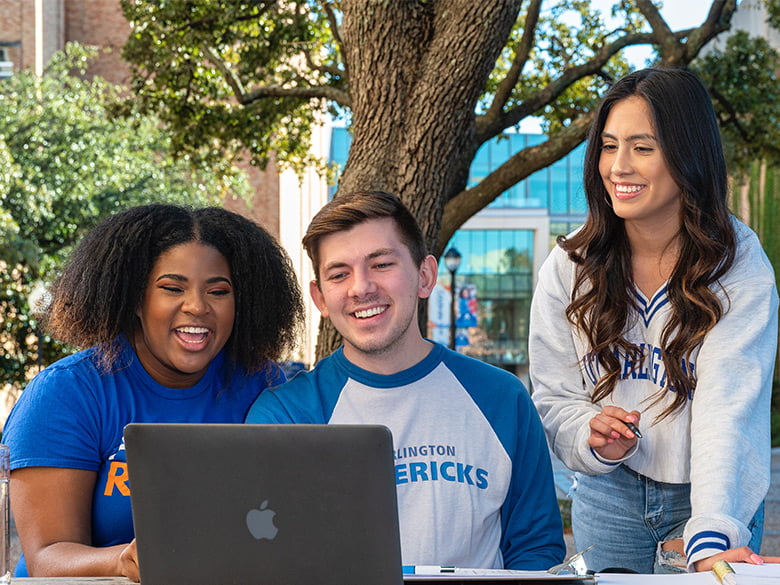 Students gather around a computer to study.