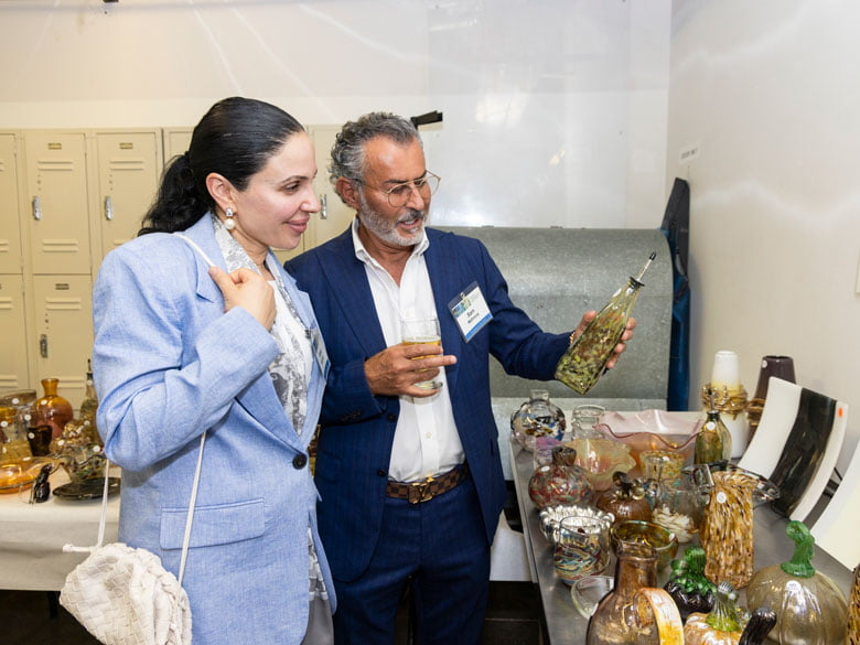 Two donor art reception guests viewing glass art on a table