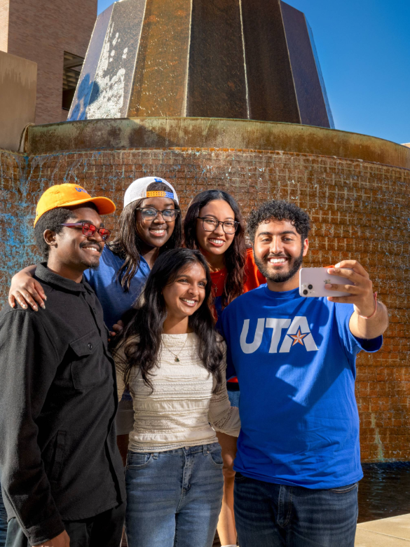 Group of five standing in front of campus fountain taking a selfie