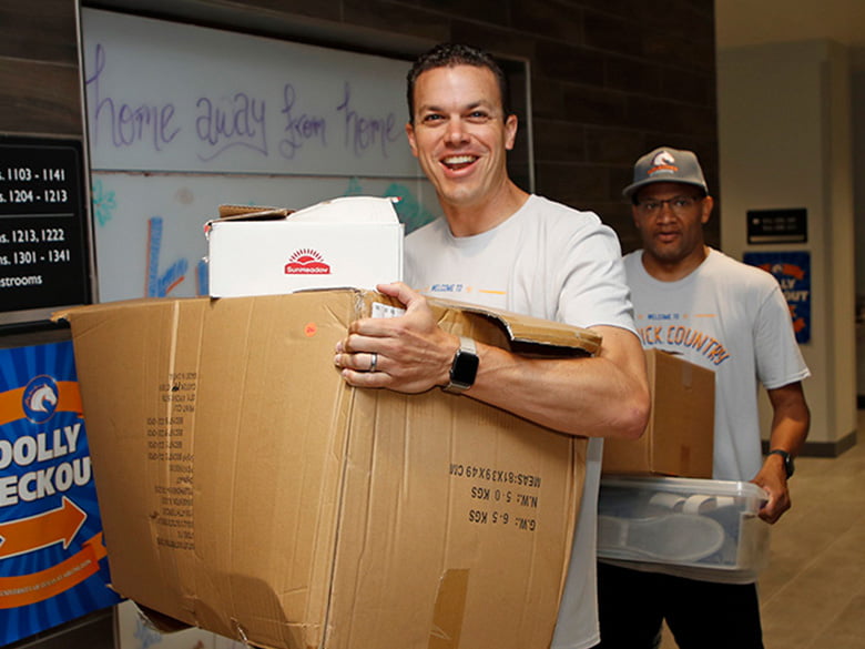 Volunteer carrying a box at Maverick Move-In day