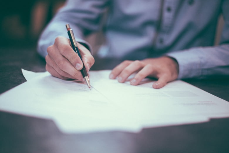 Person holding a pen and writing in paper