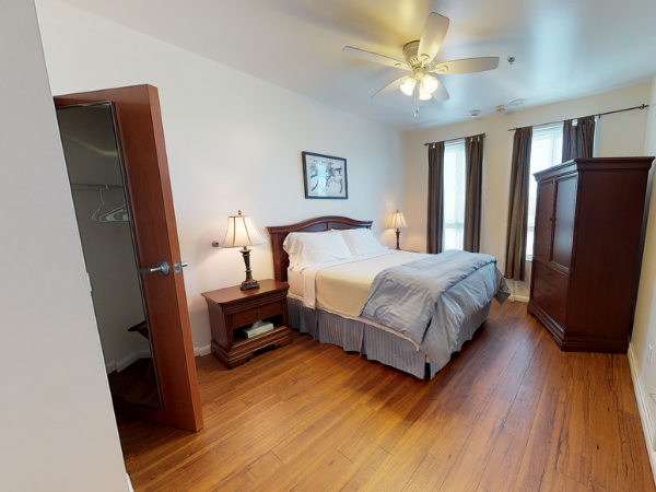 The Lofts at College Park Bedroom furnished with a bed, cabinet, bedside table and closet