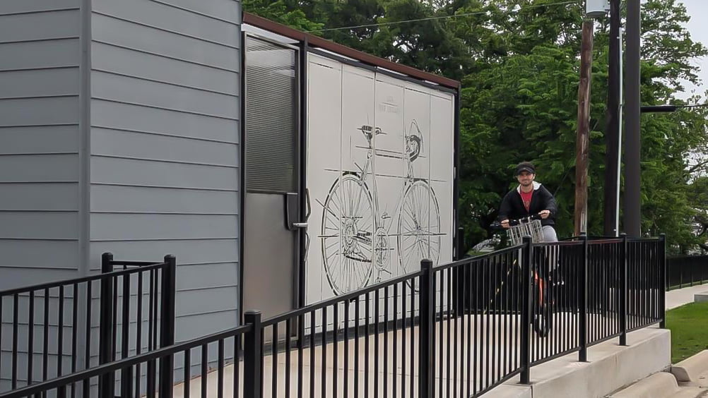 Student on bike exiting the bike barn on ramp.
