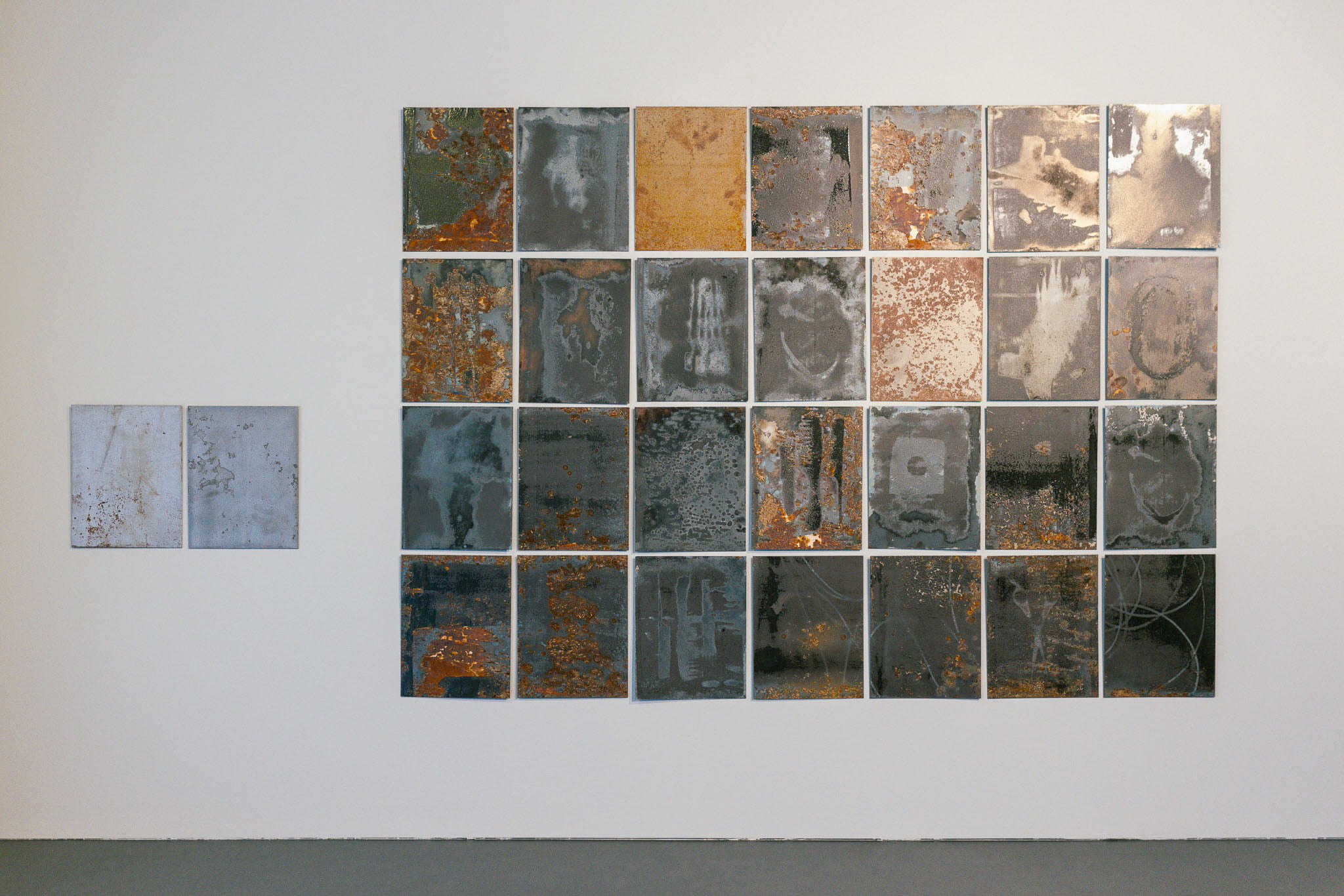 Art wall with 25 rusted and corroded square metal panels.