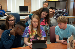 A group of people lookin in an ipad.