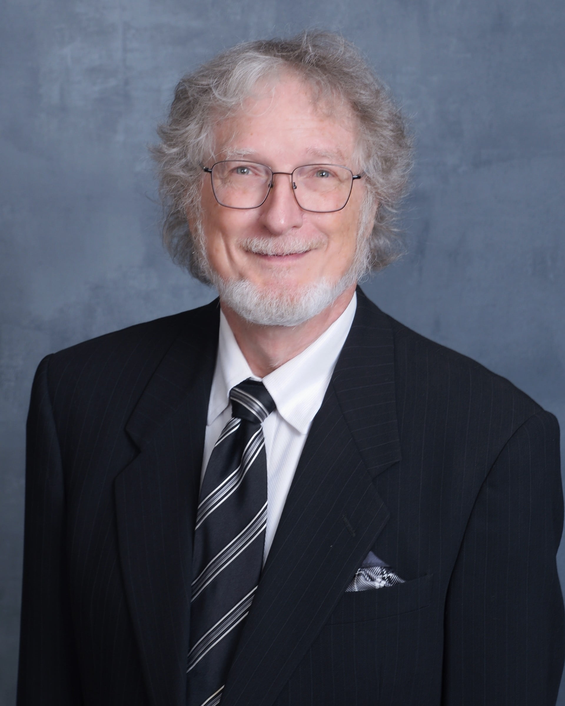 Roger Metcalf wearing a suit and glasses
