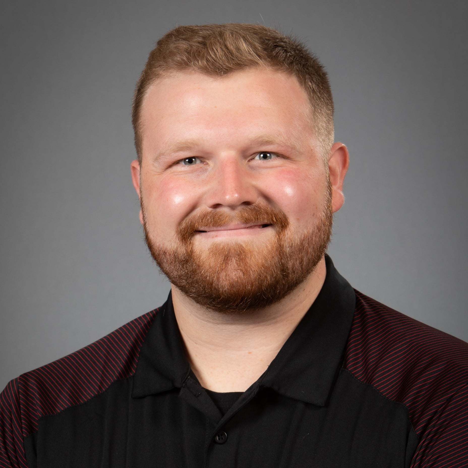 Trevor Hazlett wearing a solid button up. He has short hair and a short beard.