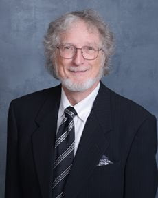 Roger Metcalf wearing a suit and glasses