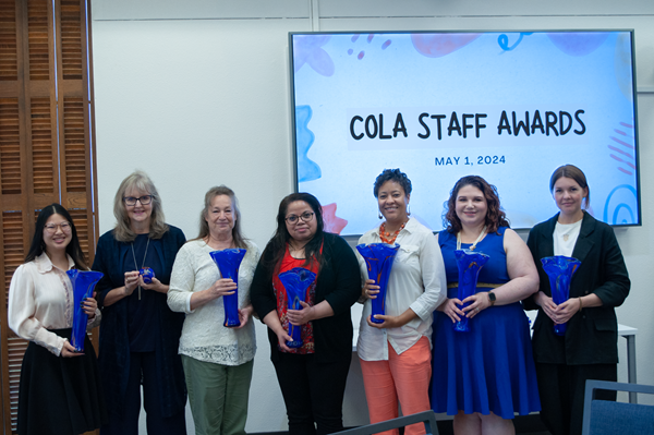 Seven people holding awards in a line. From left to right are Lily Tanner, Barrie Hill, Cathy Moseley, Vivian Skinner, Tamia Pierce, Ashley Bustillo, and Lilia Kudelia.
