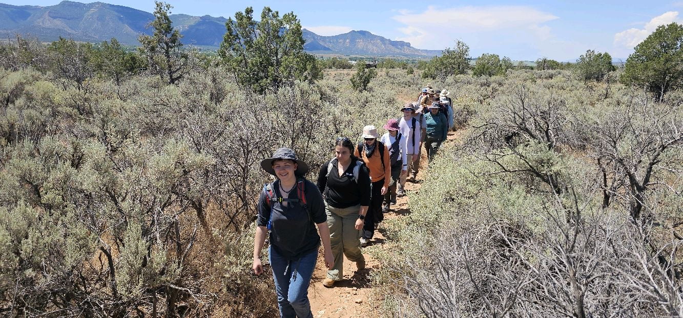 Students walking in a single file line in a field.