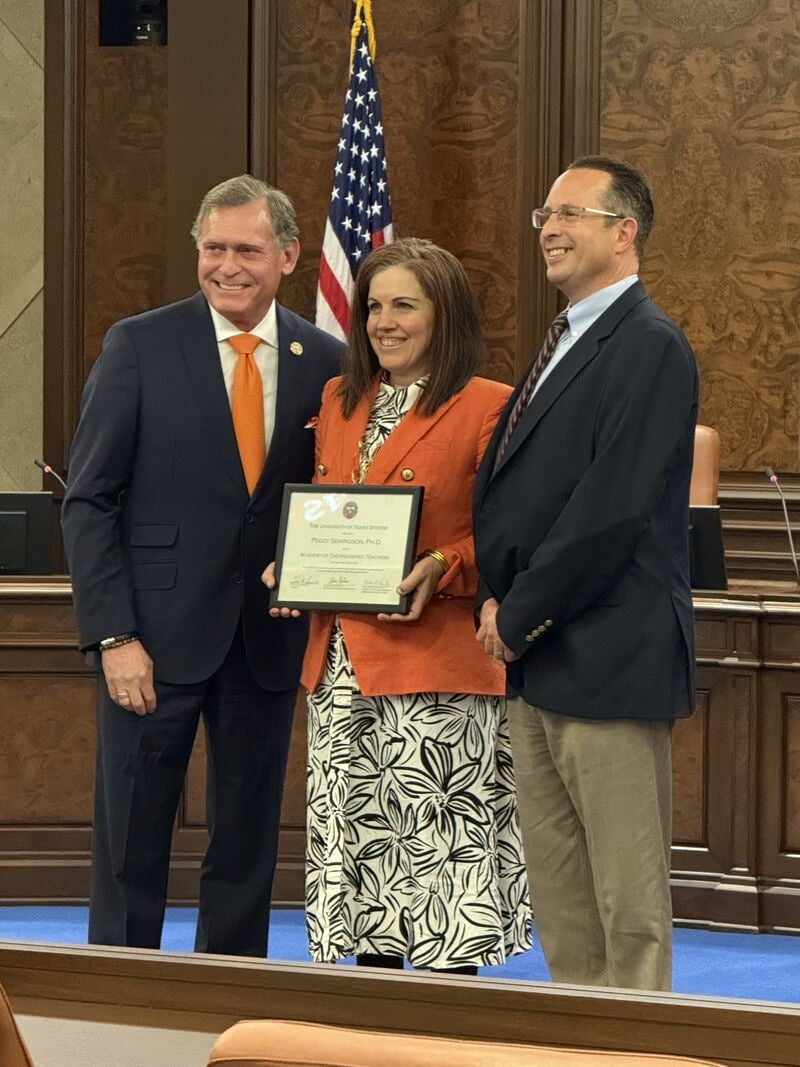 Dr. Peggy Semingson accepting her certificate as she's being inducted with two other people on either side.