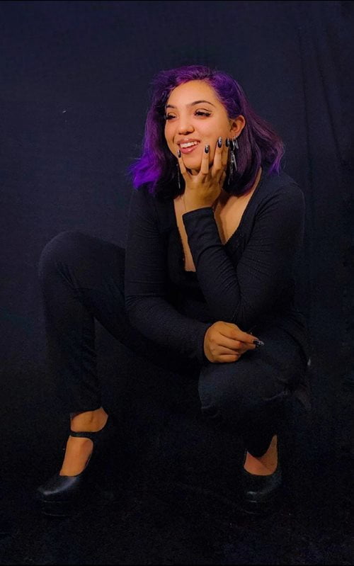 Luz Lopez looking off to the side, smiling and dressed in all dark clothes