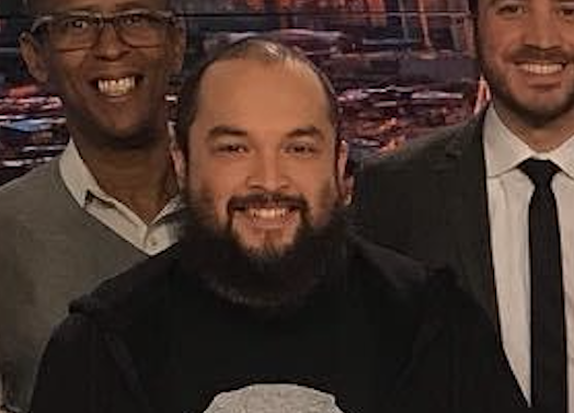 Omar Castillon in a news station, smiling with his coworkers