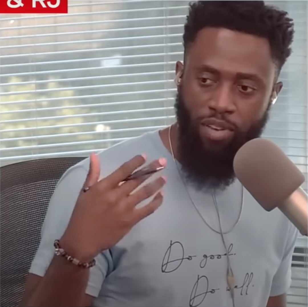 Reginald Adetula speaking into a microphone with a pen in his hand.