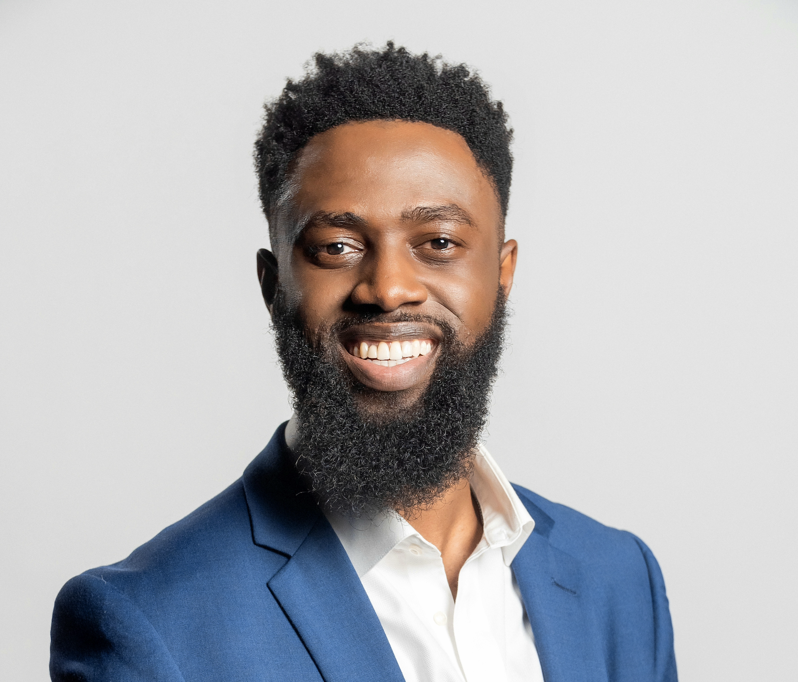Reginald Adetula wearing a suit and smiling at the camera