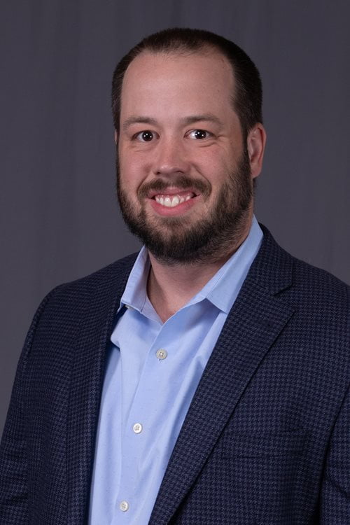 Sam Best smiling while dressed in a suit