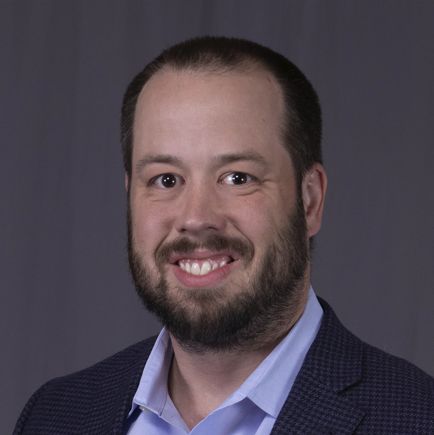 Sam Best smiling while dressed in a suit