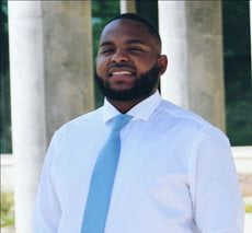Derrick Crayton wearing a button down and tie, smiling.
